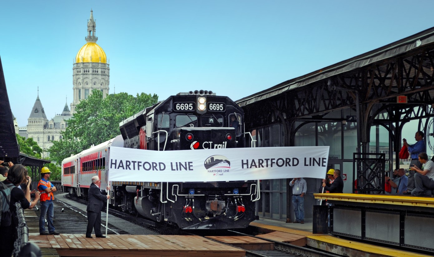 photo of a Hartford Line train moving through the opening day banner at Union Station in Hartford, Connecticut
