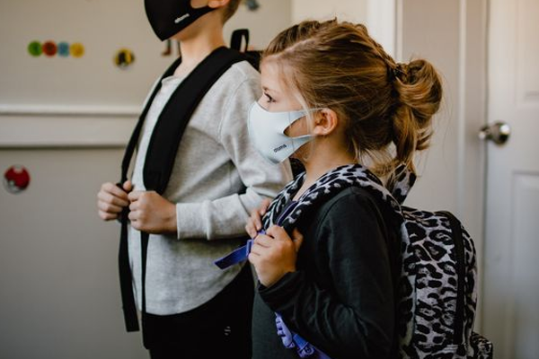 young girl wearing a mask and a backpack