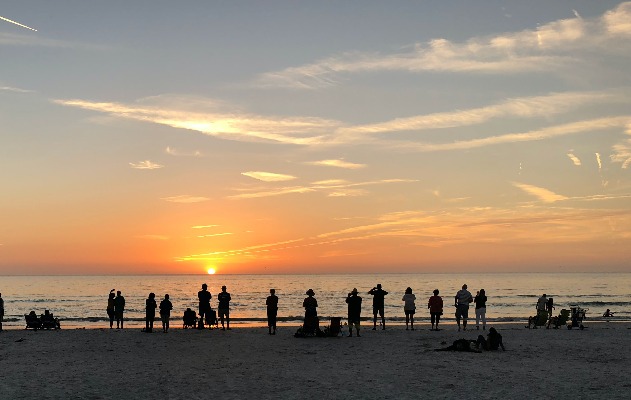 People at the beach looking at the sunset.