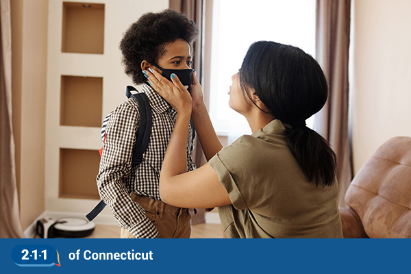 A mom holds her son who's wearing a mask. 
