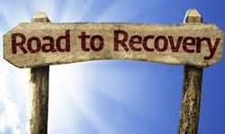Wooden road sign that reads "Road to Recovery"