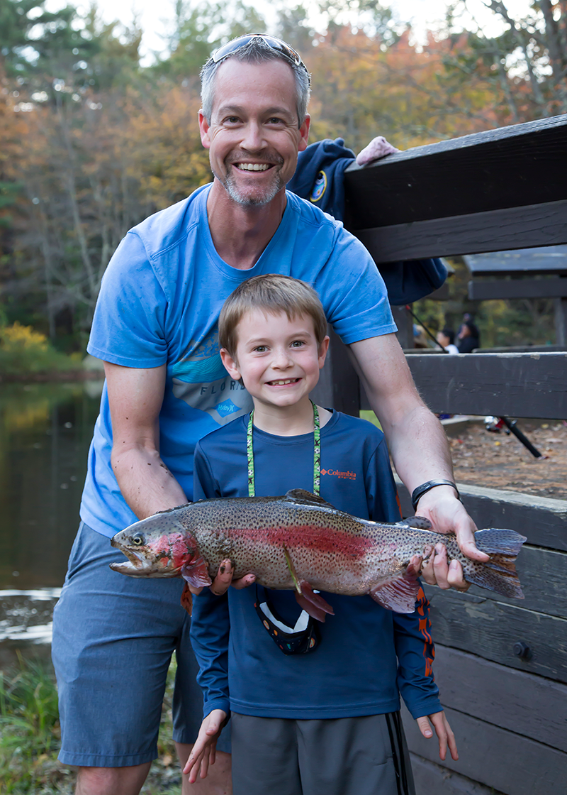 father and son holding rainbow trout