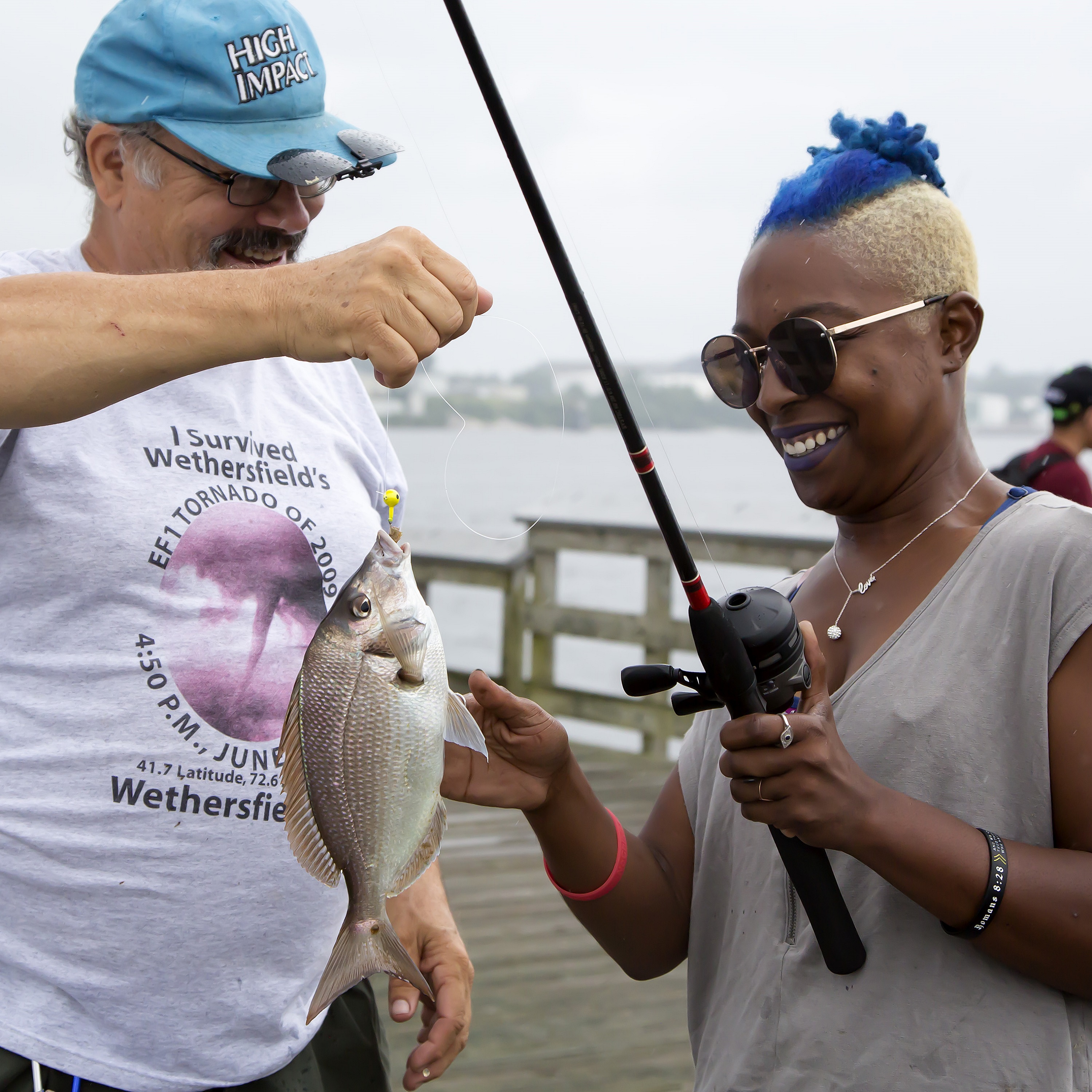 New angler catching a scup with a CARE fishing instructor on saltwater fishing day.