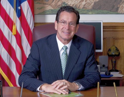 Governor Dannel P. Malloy Sitting at a Desk with an American Flag in the Background