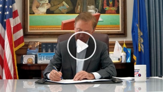 Governor Lamont sitting at his desk and signing a document