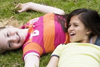 two students laying in the grass and smiling
