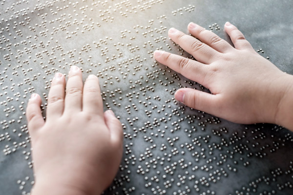 Child’s hands read Braille