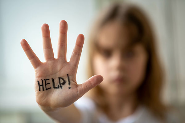 child with "help" written on her hand