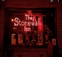 Picture of the window of the Stonewall Inn at night, the sign lit up in red neon lights
