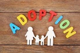 Photo of the word "adoption" spelled out in magnets above a cutout of a family on a wood background