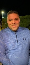Photo of Angel Robles in a blue sweatshirt.  He is smiling.