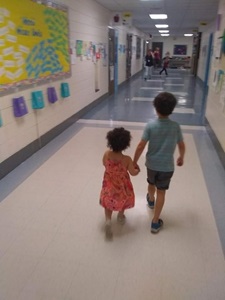 Joseph's son holds his sister's hand as they walk down a hallway