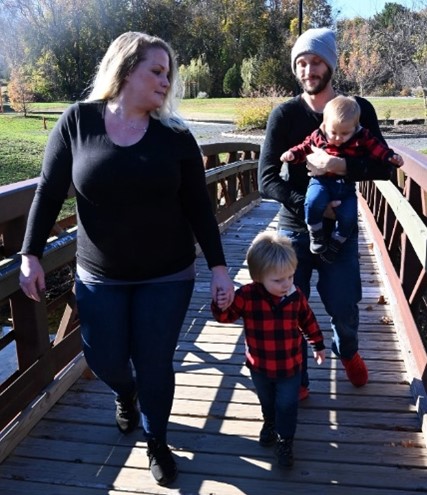 A group of people walking on a wooden bridge Description automatically generated with medium confidence