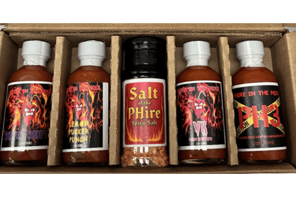 Image of five hot sauces bottles made by Phire in the Hole, part of a recall due to potential risk of botulism. Colorful packaging indicates several flavors including P.I.T.H BBQ VK Vamps Kryptonite Lemon Pucker Punch The Hawaiian Ghost Boo Bee Q Reaper Creeper