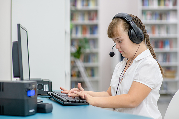 young girl with syndrome down uses computer at library