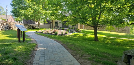 Paver walkway leading to the museum visitor center, with two interpretive signs on the lefthand side. 