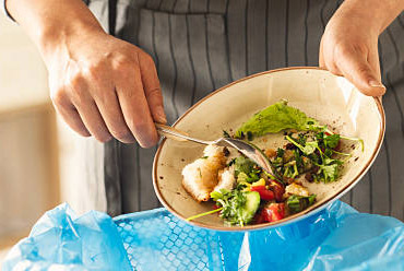 Person scraping food waste into compost bag