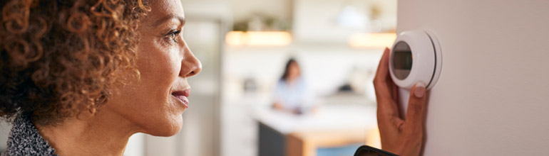 Woman adjusting smart home thermostat