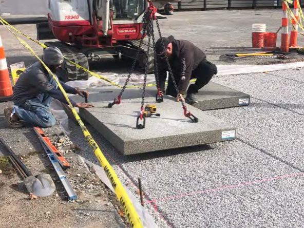 The porous concrete pad is made up of individual panels. One is being carefully placed here (Maura Robie, ECCD).
