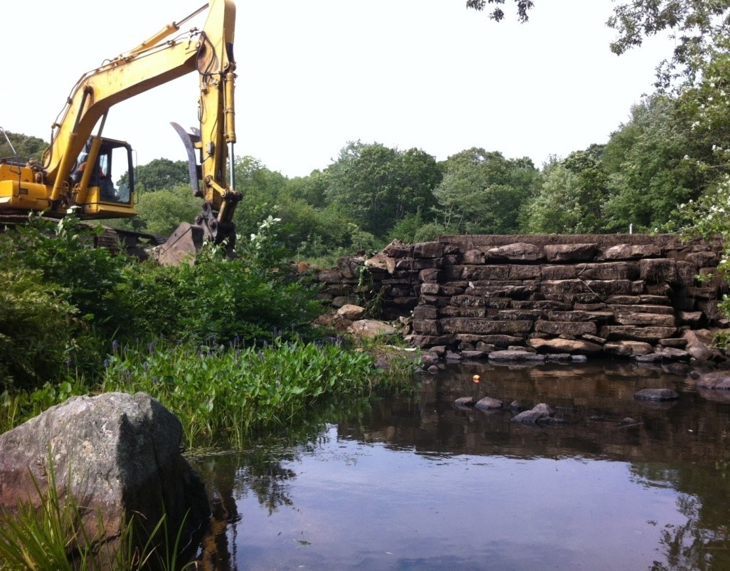A backhoe demolishing a dam