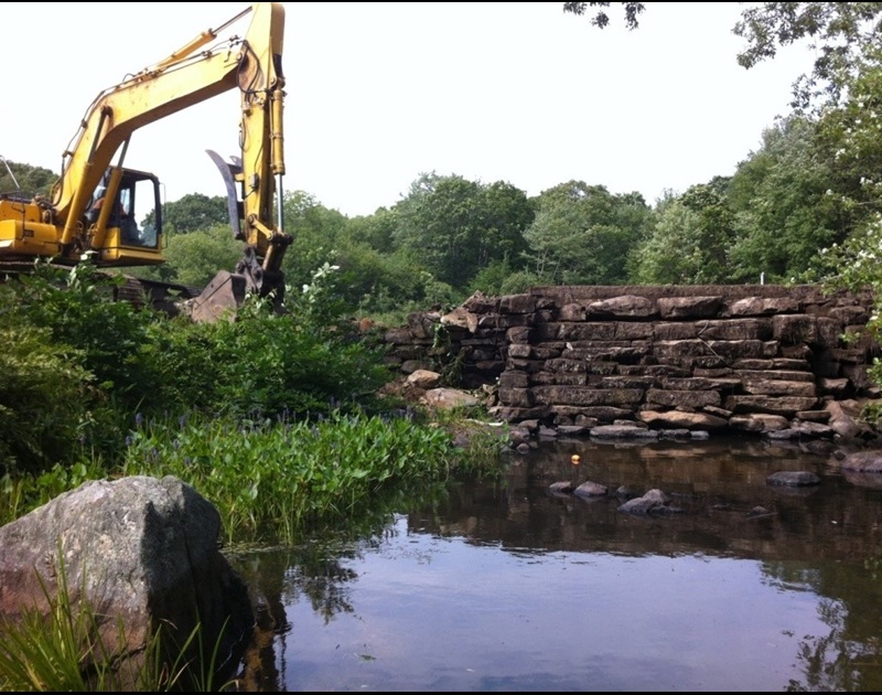 A backhoe demolishing a dam
