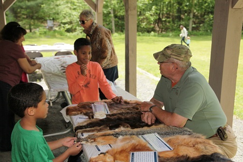 Two children learn about animal furs with a Master Wildlife Conservationist