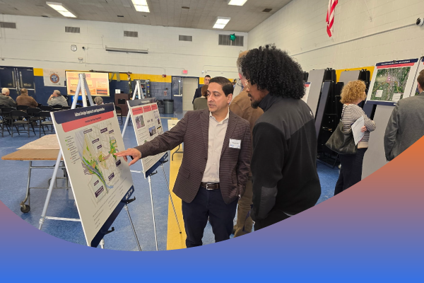 Two people discussing a display board at a public meeting.