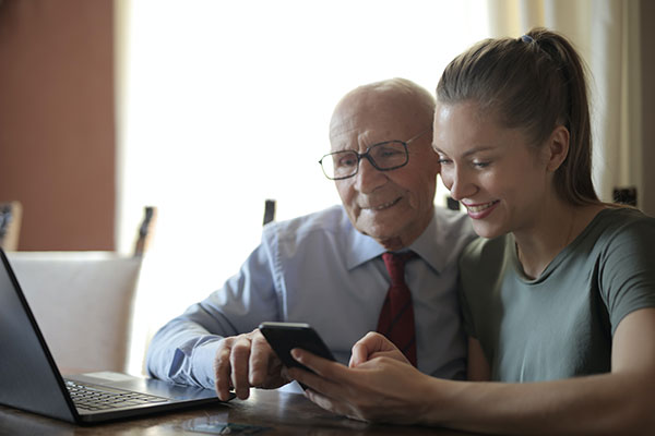 Young woman assisting older man with mobile device