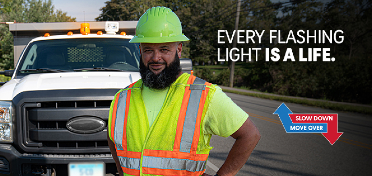 every flashing light is a life - a construction worker posing in-front of a safety vehicle