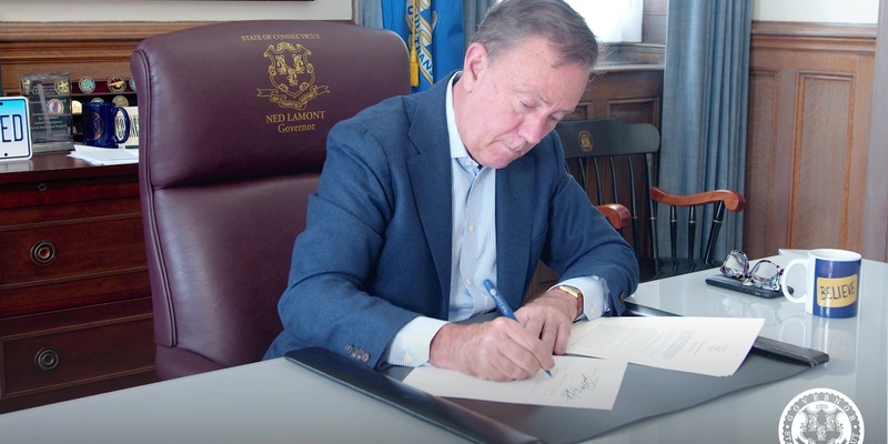 Governor Lamont at his desk signing reproductive rights legislation