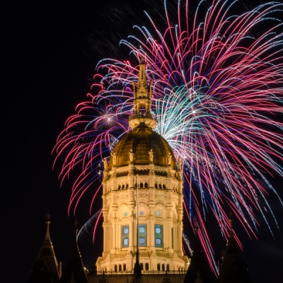 Dome of the Connecticut State Capitol building with fireworks in the background.