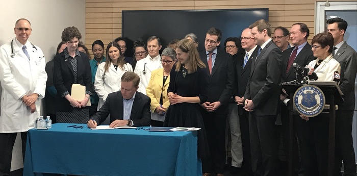 Surrounded by state legislators, healthcare advocates, and business and community leaders, Governor Ned Lamont signs two executive orders aimed at reducing healthcare costs for Connecticut residents. [Download image in high quality]