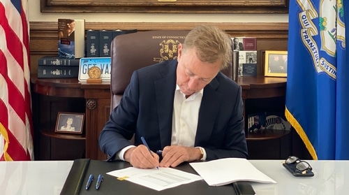 Governor Lamont at his desk signing legislation