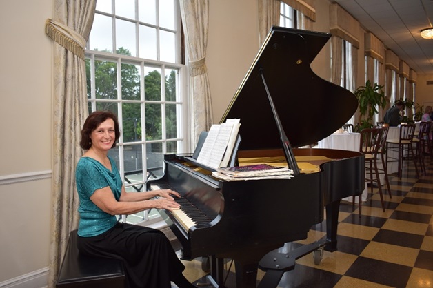 Dr. Gale Ridge, seated at a grand piano in a reception hall.