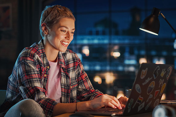 young attractive woman using laptop computer in stylish loft apartment in the evening
