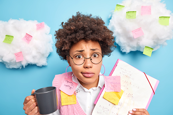 Puzzled young women with glasses holding up a clipboard and coffee cup with many post-its attached to her and artificial cotton clouds on cyan background.