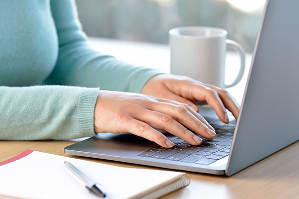 Woman writing in a gray laptop