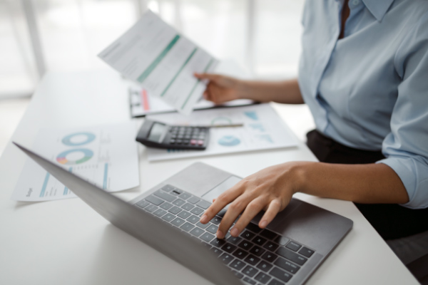 Woman working at computer with documents.
