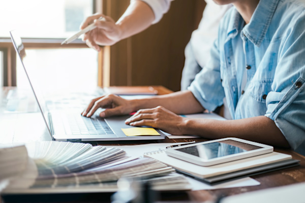 Two work colleagues looking for upcoming events in a web page on a laptop.