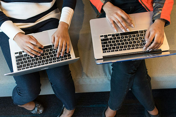two people typing on laptops
