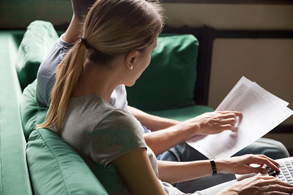 woman and man sitting on couch reading a document