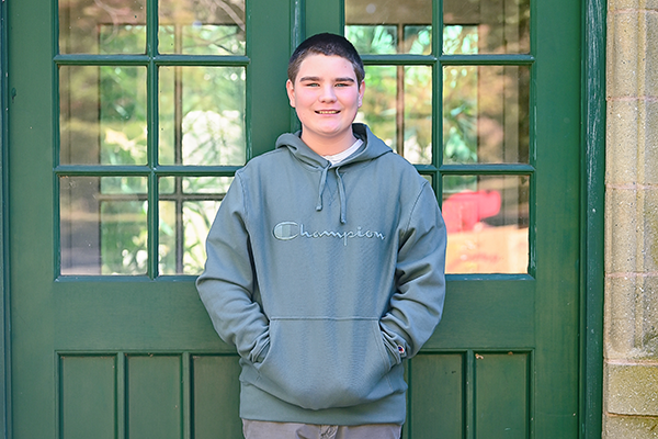 Young white boy wearing a champion hoodie smiles