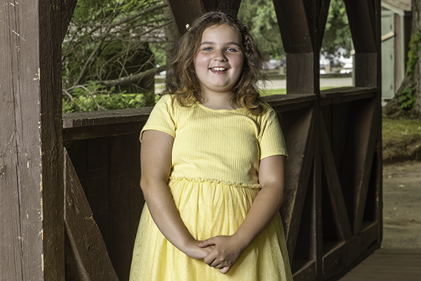 Young girl in a yellow dress smiling.