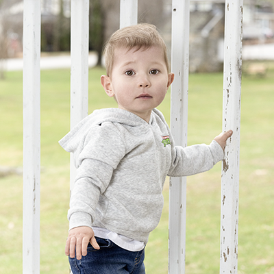 baby boy holds fence