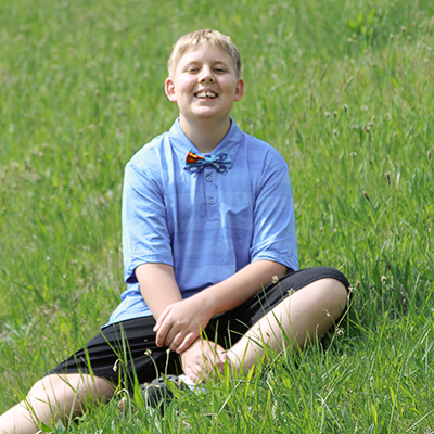 a young blond boy sits in a sunny field