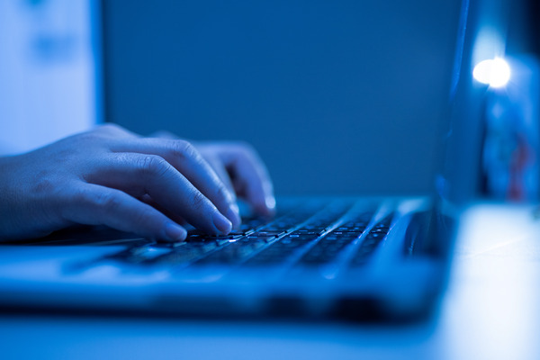 Image of hands typing on keyboard, with a blue tint