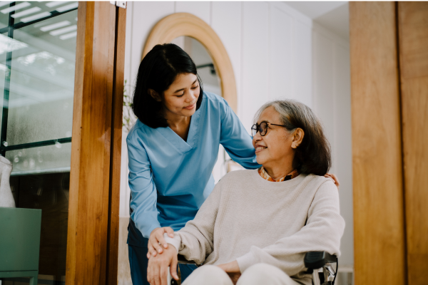 Image of homemaker-companion smiling at elderly woman who is sitting in a wheelchair