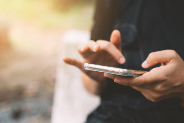 Image of individual using a cellphone to imply sports betting on a mobile phone