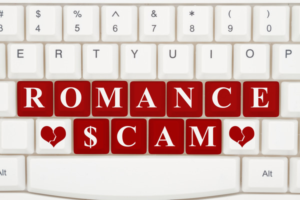 Image of keyboard with red keys that spell out Romance Scam with broken hearts