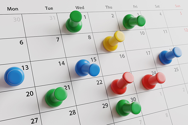 Thumbtacks on different dates of a calendar.
